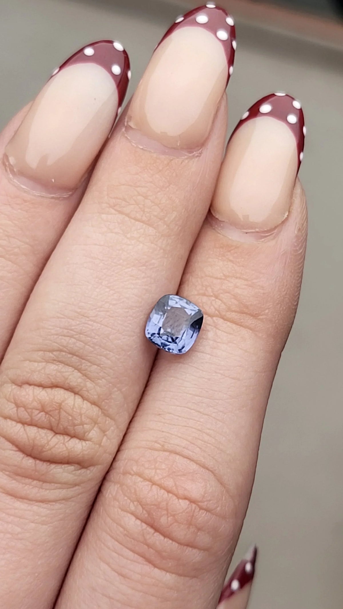 Cushion-cut blue sapphire gemstone held in hand, showcasing brilliance and elegance for fine jewelry.