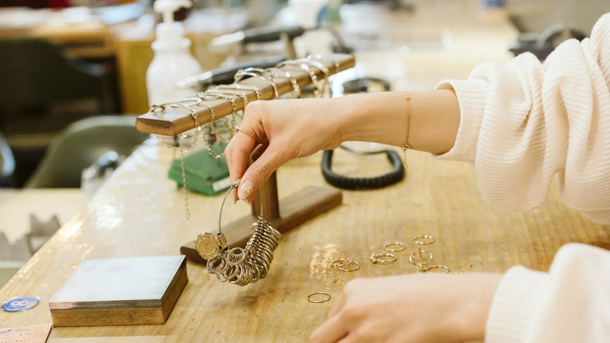 Woman selecting gold rings from a jewelry display stand in a workshop setting