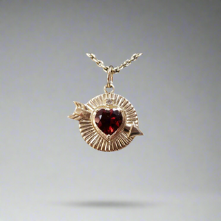 Red Garnet Heart With Brilliant Cut Diamond 14k Gold Pendant Shown With Gold Chain Against Grey Background 