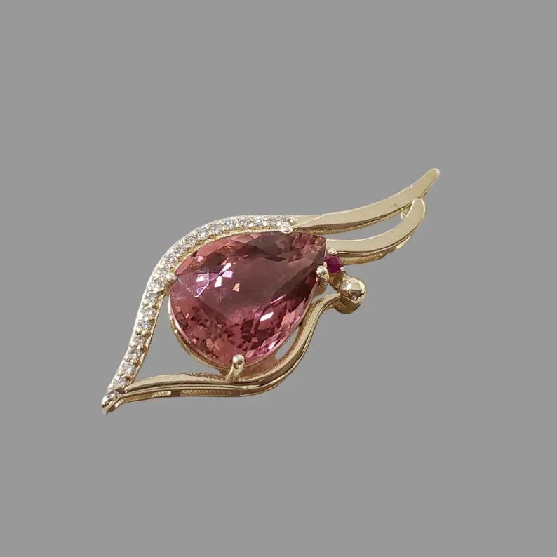 Elegant gold brooch with pear-cut pink gemstone and diamond accents, luxury jewelry accessory