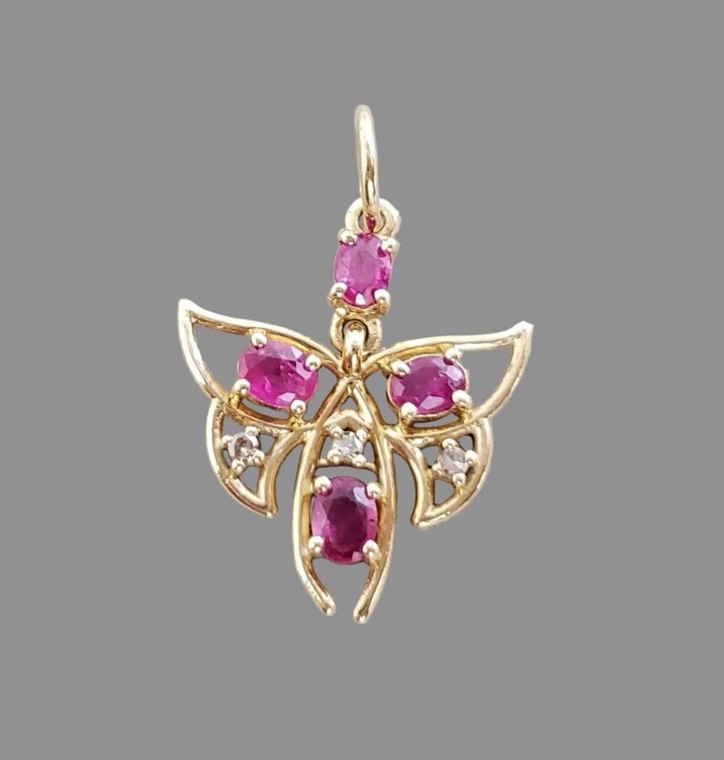 Handmade ruby butterfly charm shown in daylight
