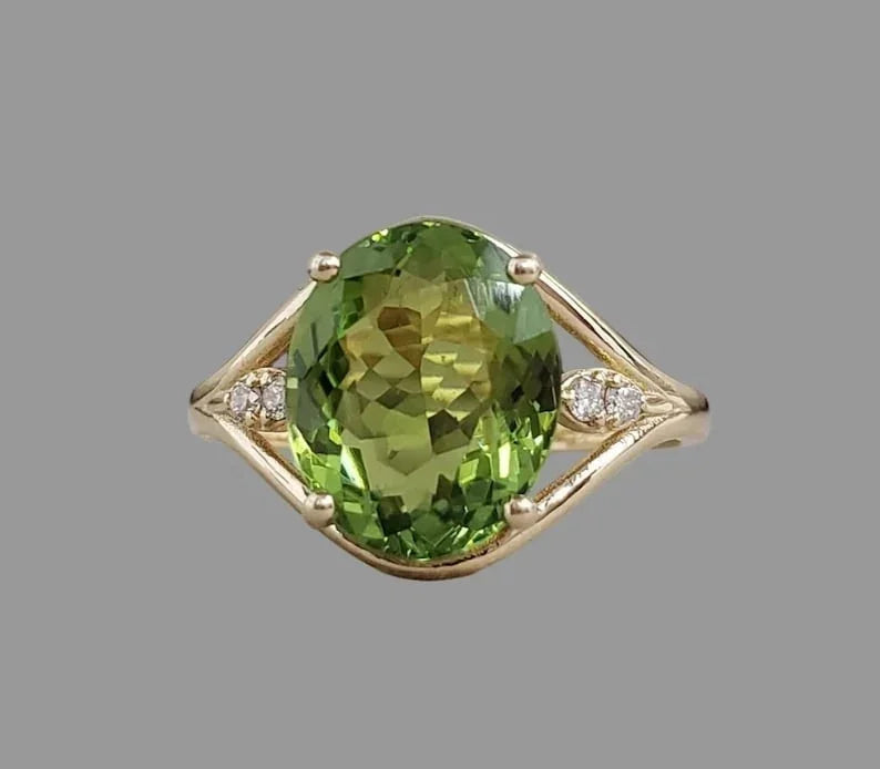 Elegant gold ring with oval green gemstone and diamond accents, perfect for sophisticated jewelry lovers.
