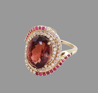 Elegant gold ring with oval red gemstone, diamond and ruby accents, luxury jewelry design