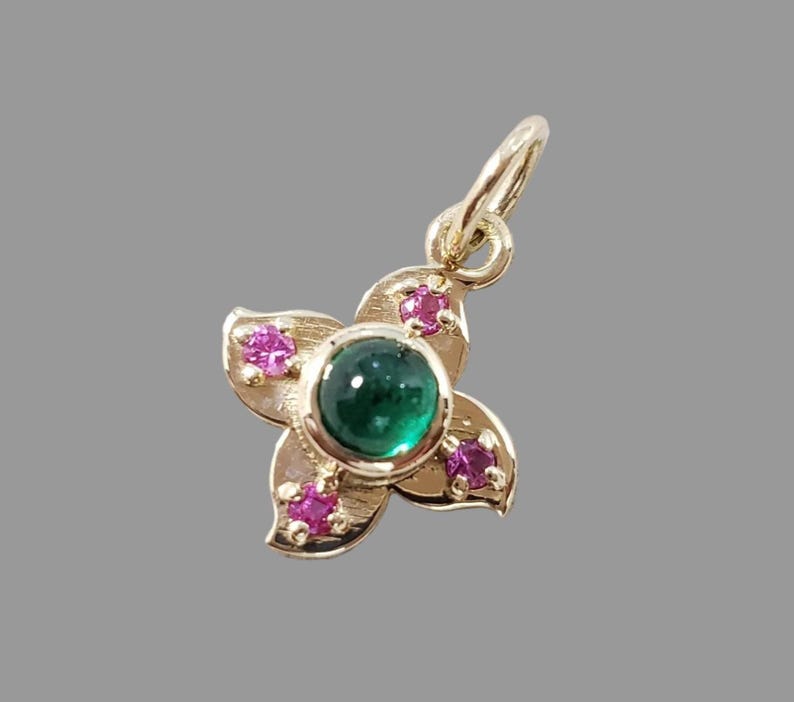 Cabochon emerald charm with four ruby petals, close-up