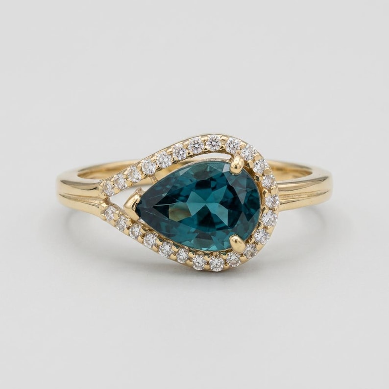Blue spinel ring with pear diamond halo in 14K yellow gold