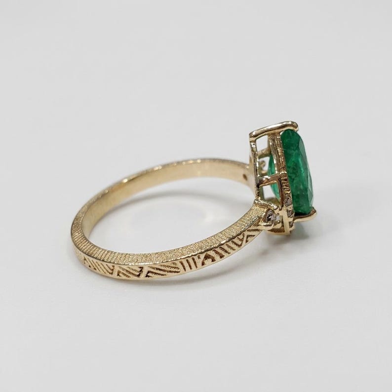 Pear-cut green emerald and diamond ring shown in daylight