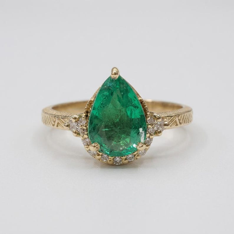 Pear emerald ring with diamonds on an engraved 14K yellow gold band