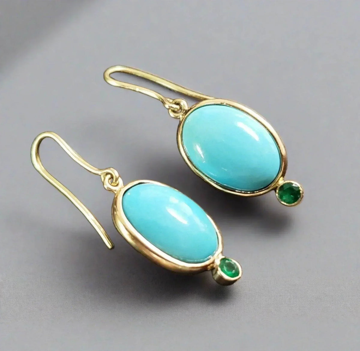 Elegant gold earrings with oval turquoise stones and emerald accents, perfect for sophisticated jewelry lovers.