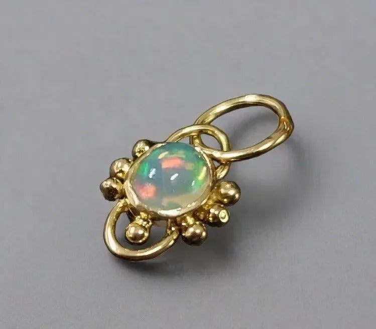 Elegant gold pendant with vibrant opal gemstone, showcasing luxury jewelry design