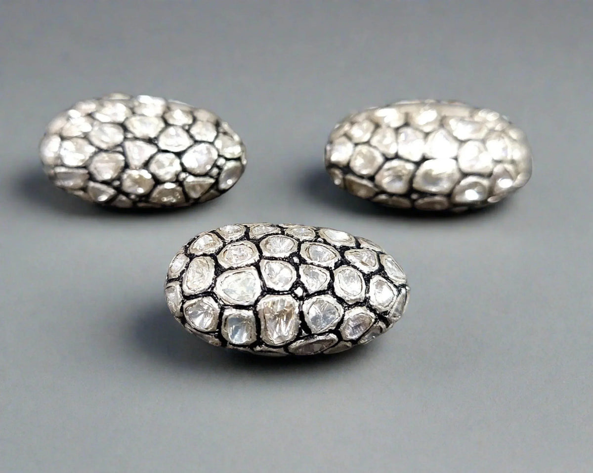 Elegant diamond-encrusted oval jewelry pieces with textured silver setting, perfect for luxury accessories.