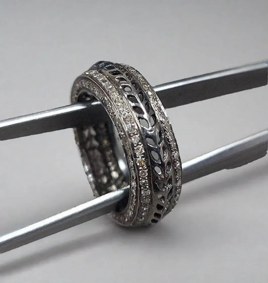 Elegant diamond-encrusted filigree ring held by tweezers, showcasing intricate craftsmanship and sparkle.