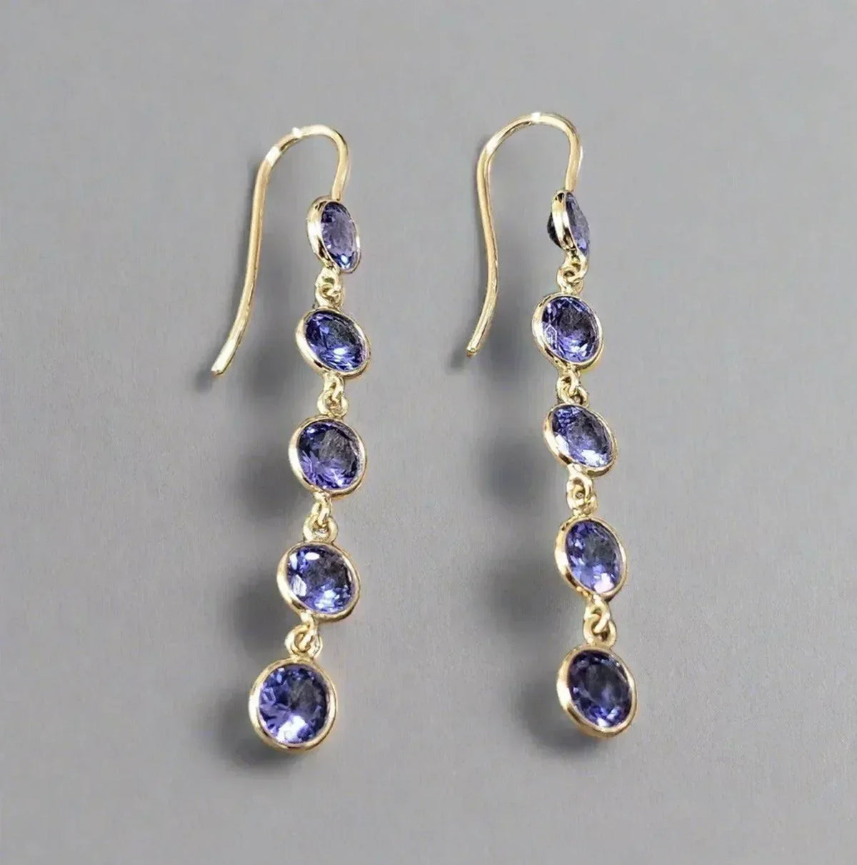 Elegant gold drop earrings with five oval tanzanite stones, perfect for sophisticated jewelry lovers.