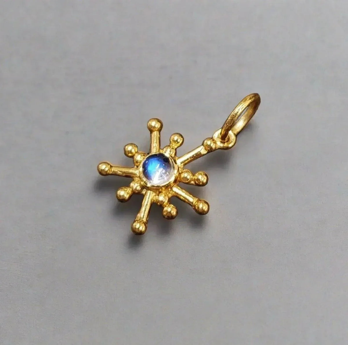 Gold starburst pendant with blue gemstone, elegant jewelry accessory