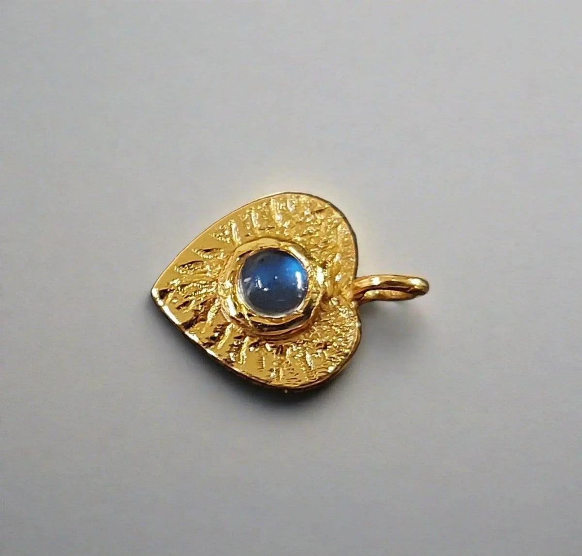 Gold evil eye pendant with blue gemstone, textured design for elegant jewelry collection