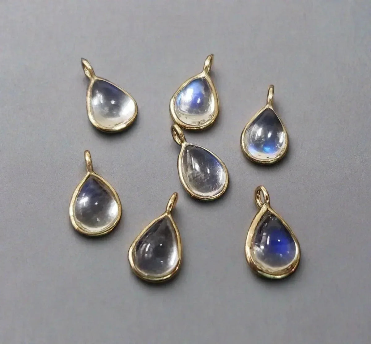 Teardrop moonstone pendants in gold settings, elegant jewelry accessories with blue sheen