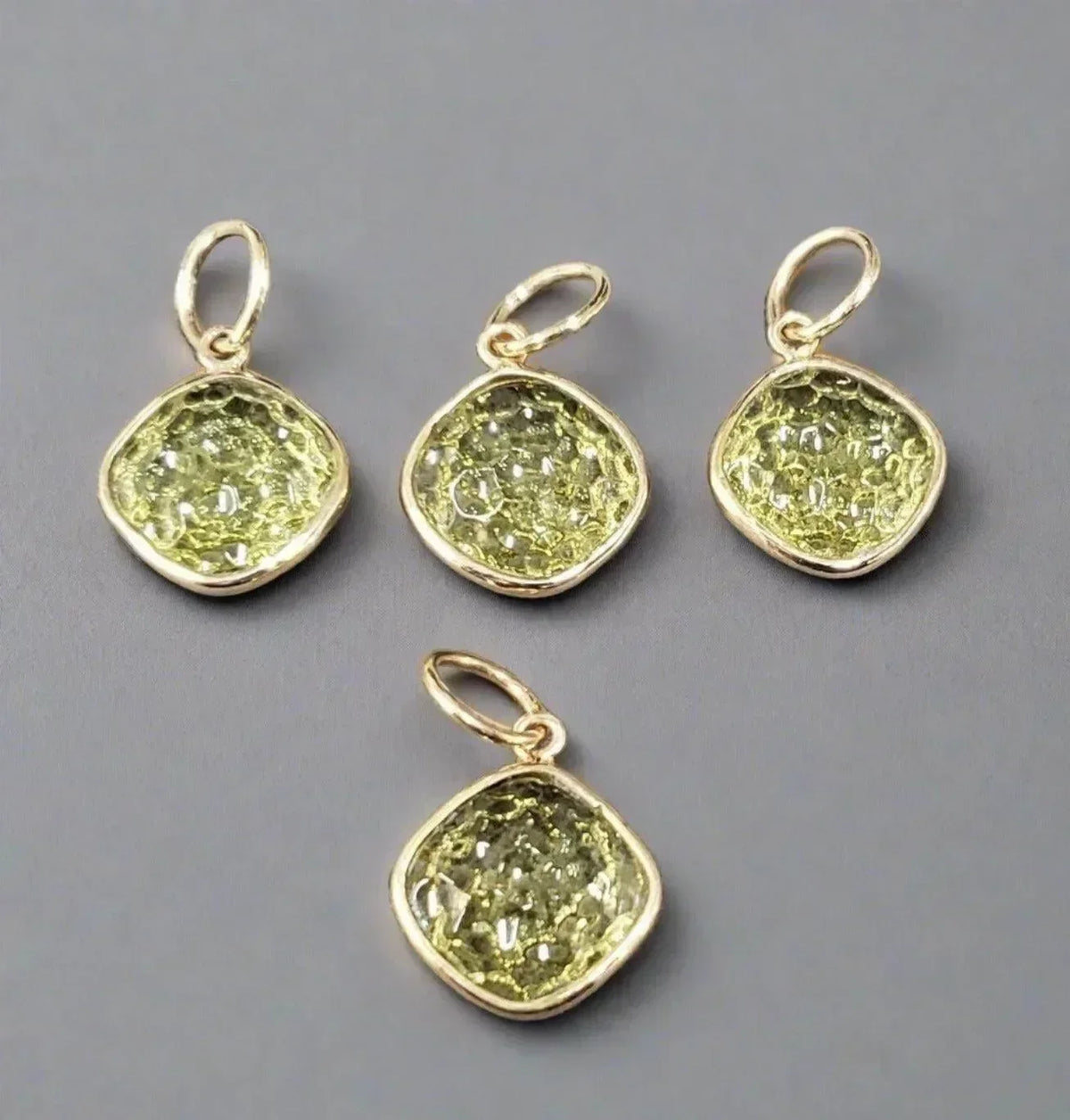 Four gold pendants with textured green gemstones, elegant jewelry accessories